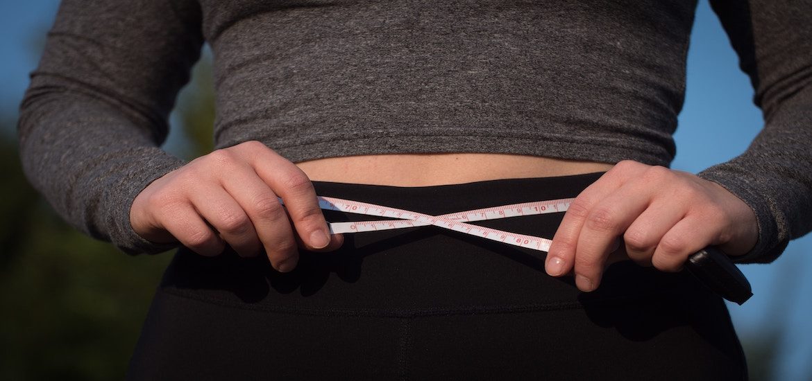 Picture of measuring tape encircling a fit stomach.