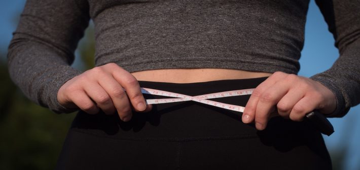 Picture of measuring tape encircling a fit stomach.