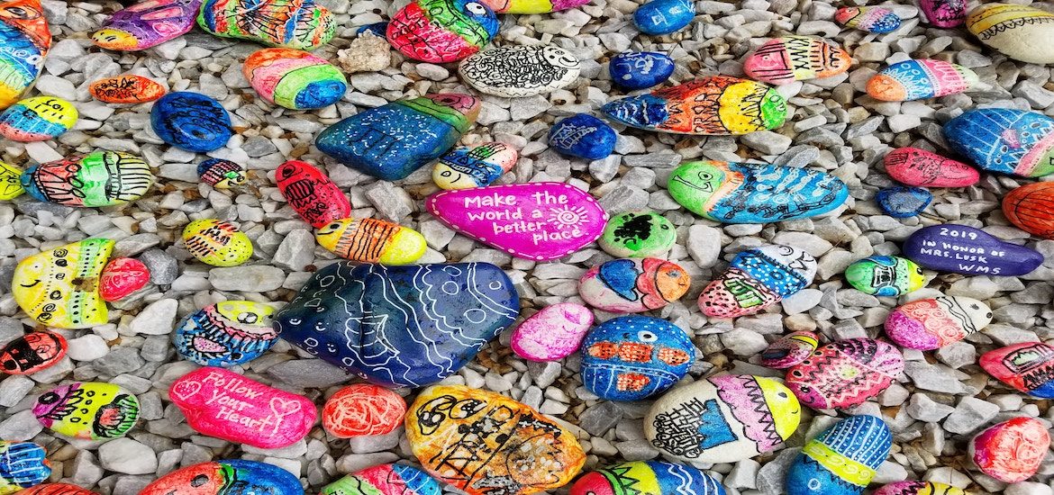 Colorful rock on rocky shore. One rock with word kindness stands out/