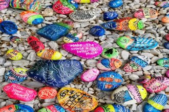 Colorful rock on rocky shore. One rock with word kindness stands out/